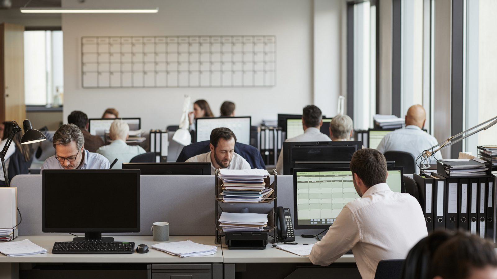 A busy open-plan accounting practice during a deadline period, several occupied desks.