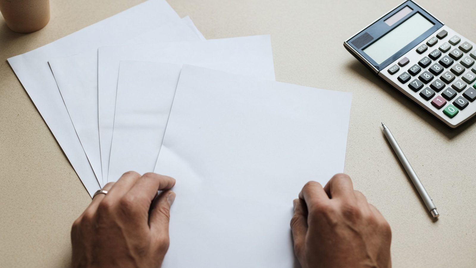 An accounts payable desk from above with three overlapping documents, a pen and a calculator.